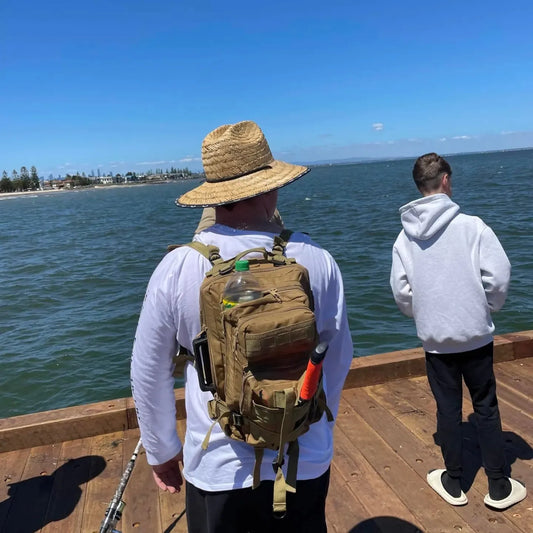 Hiker wearing the Koala Premium Day Pack along a waterfront boardwalk.